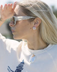 Woman wearing sunglasses and a white shirt with a lighthouse design.