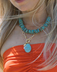 Close-up of a person wearing a turquoise beaded necklace with a shell pendant necklace