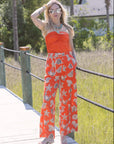 Woman in an orange outfit with a pattern standing on a wooden bridge in a natural setting