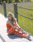 Woman in Bloo Linen Pant sitting on a wooden dock by a grassy area