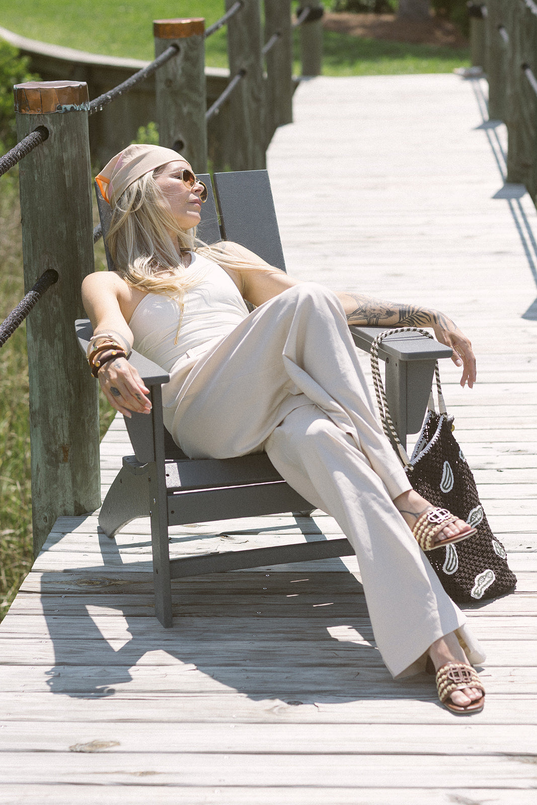 Woman sitting on a wooden deck wearing a white outfit with a colorful headscarf.