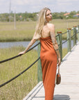 Woman in an orange dress standing on a wooden bridge with a scenic background