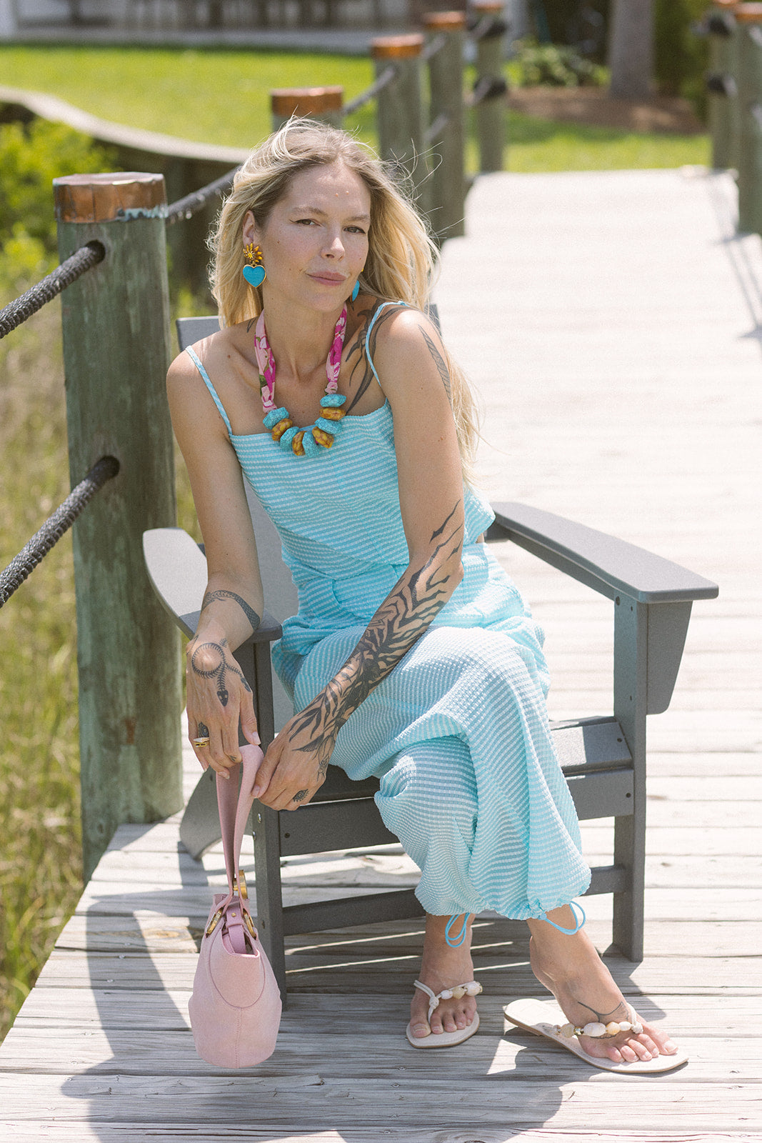 Woman in a blue set sitting on a wooden bench outdoors with Gretta Earrings and Cely Sandals