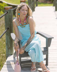 Woman in a blue set sitting on a wooden bench outdoors with Gretta Earrings and Cely Sandals