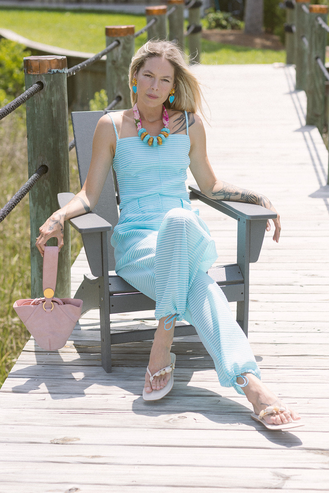 Woman in a light blue matching set sitting on a wooden bench outdoors.