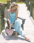 Woman in a light blue set sitting on a wooden bench outdoors.