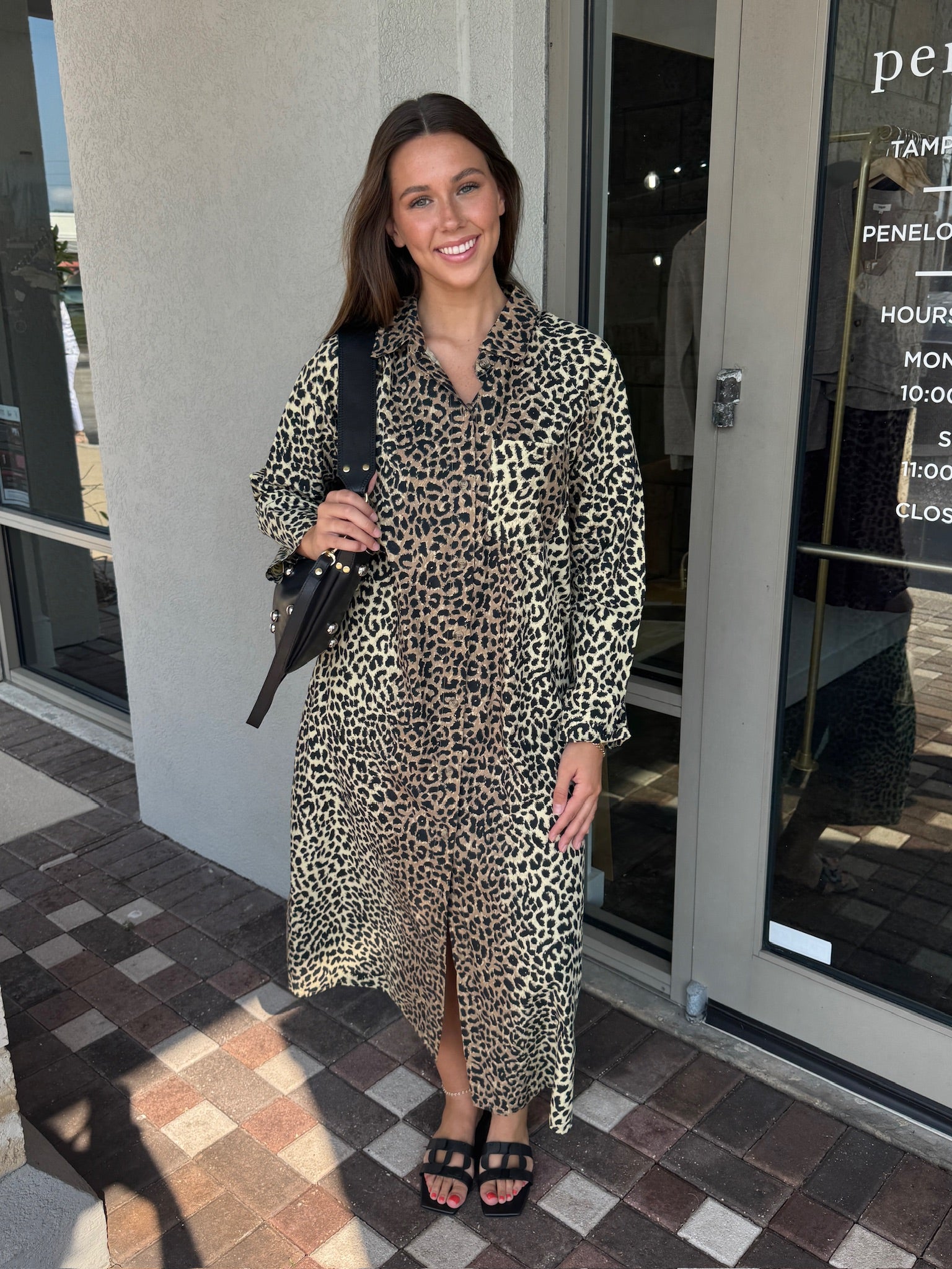 Woman in a leopard print dress standing outside a store