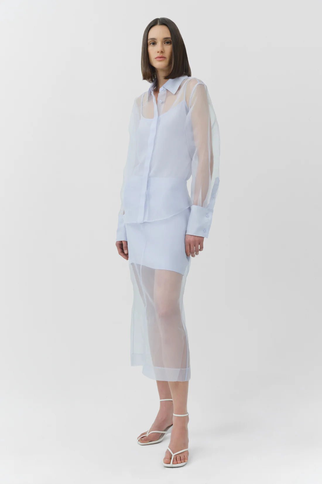Woman wearing a light blue sheer skirt and top with a white background