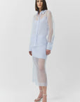 Woman wearing a light blue sheer skirt and top with a white background