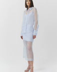 Woman wearing a light blue sheer top and skirt with a white background