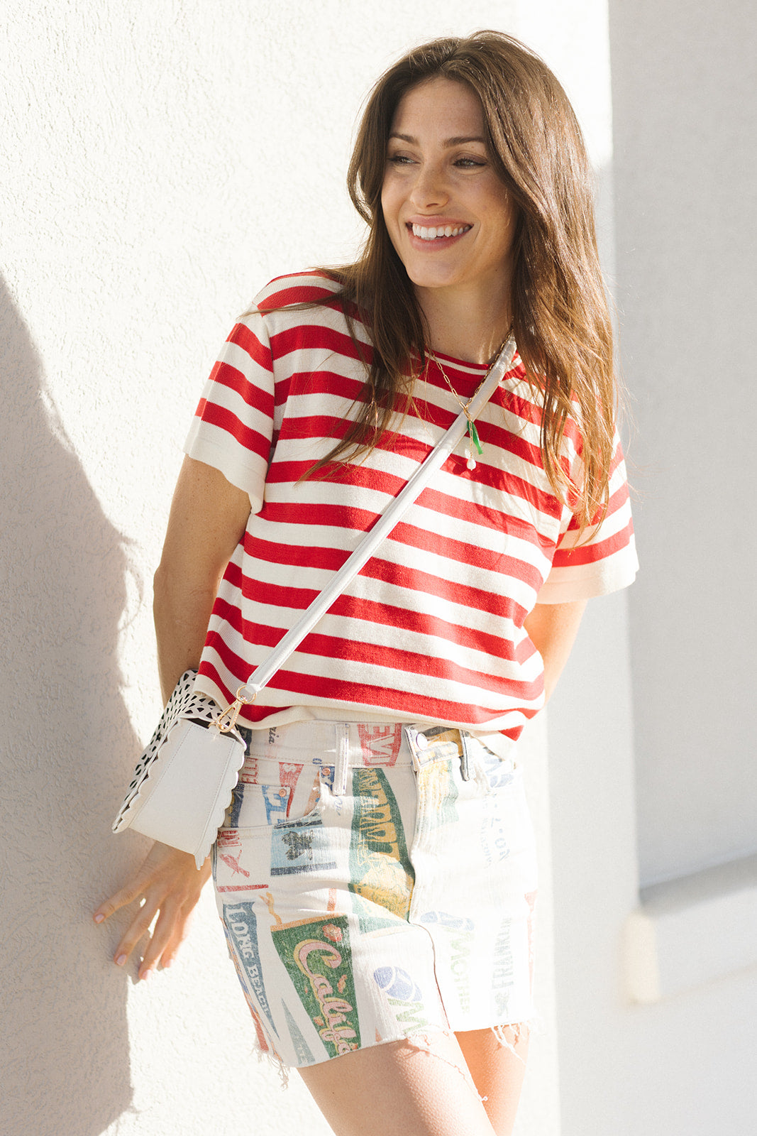 Woman wearing a red and white striped shirt with colorful shorts, standing against a light background.