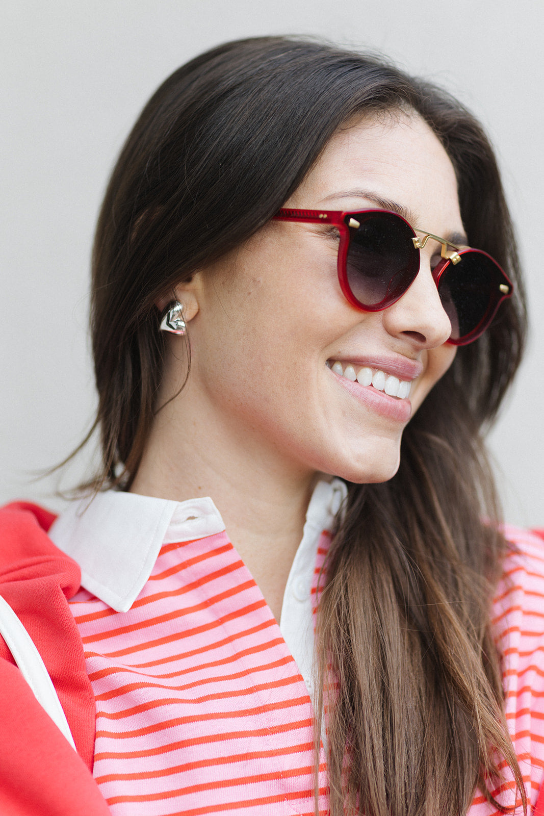 Woman wearing red heart-shaped sunglasses and a red and white striped shirt.