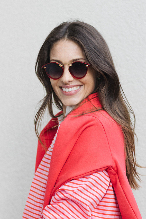 Woman wearing a red and white striped dress with a red jacket against a gray background
