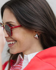 Woman wearing red sunglasses and a red jacket with a blurred background