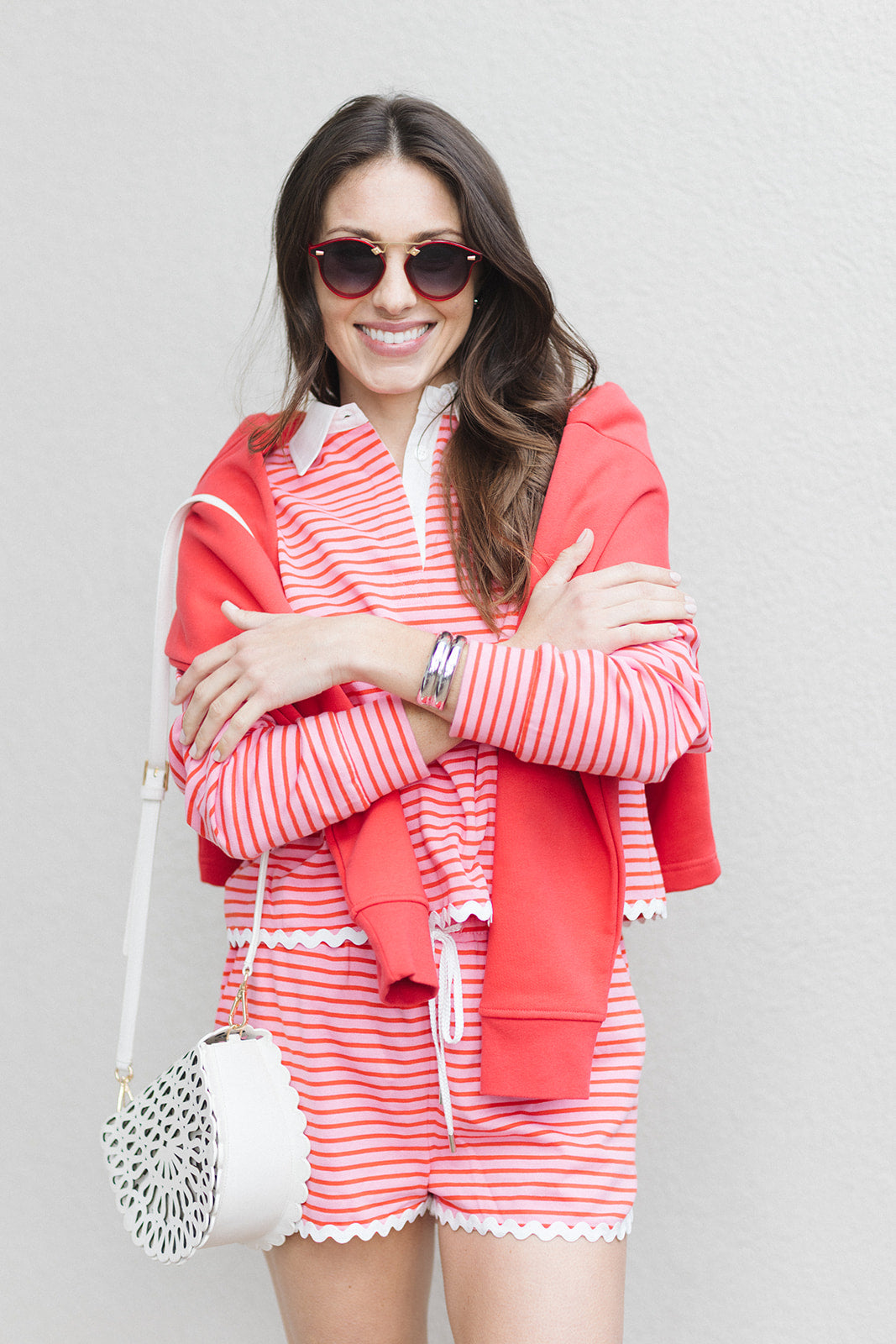 Woman wearing a red and white striped outfit with sunglasses against a gray background