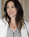 Woman wearing a white blazer over a striped shirt with a neutral background