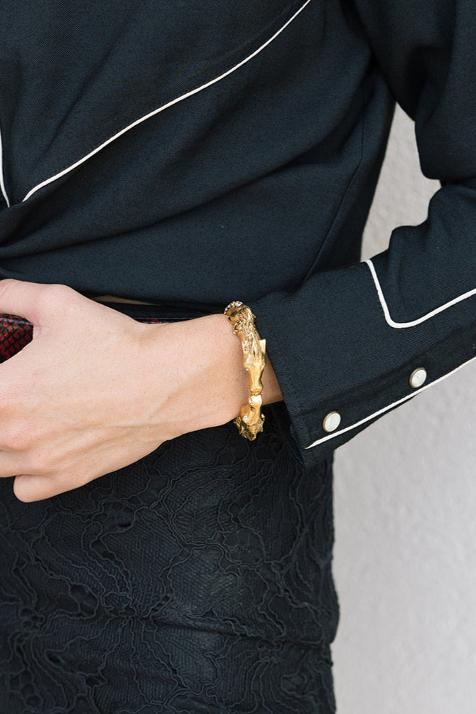 Person wearing a gold bracelet with a black outfit