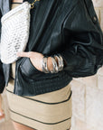 Early oversized faux leather coat on a model with a silver bag and mini dress wearing sunglasses, close up