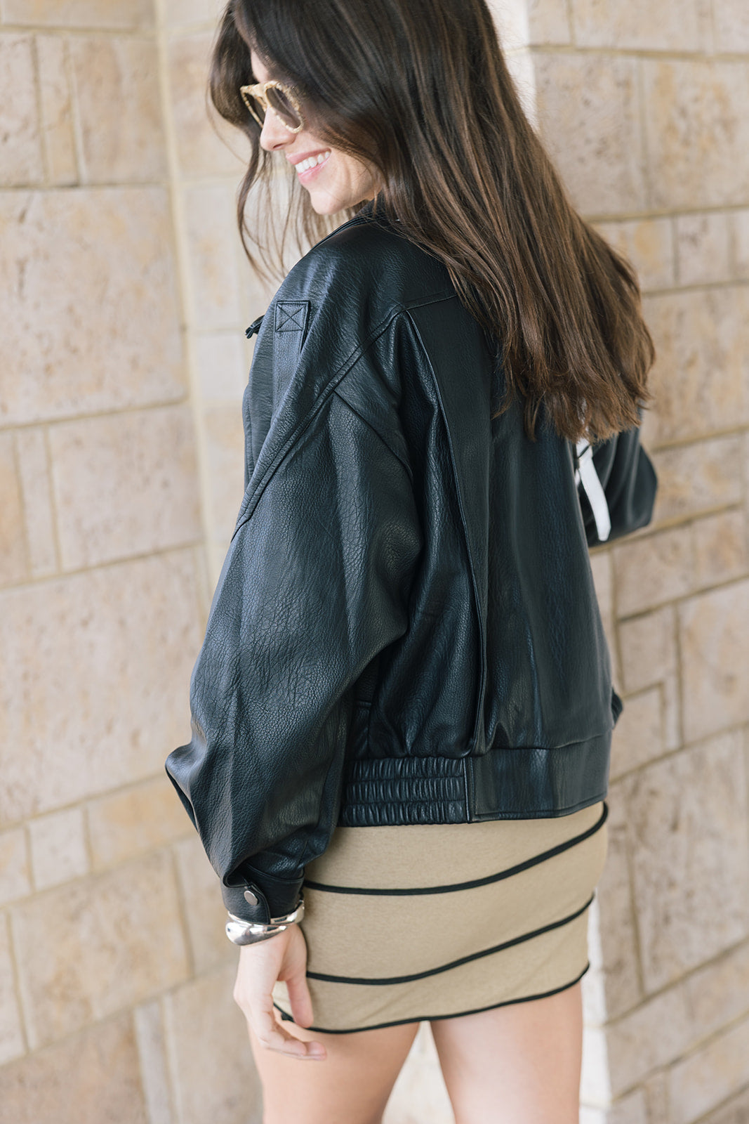 Early oversized faux leather coat on a model wearing a mini dress side / back view