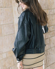 Early oversized faux leather coat on a model wearing a mini dress side / back view