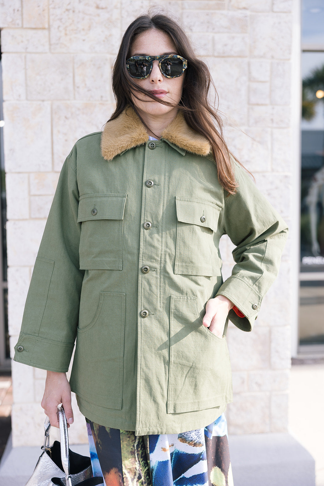 Woman wearing The Quilted Liner Parka green coat with a fur-lined hood outdoors front view