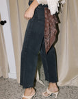 The silky bandana in the pocket of black jeans on a model with heels and a fringe cardigan 