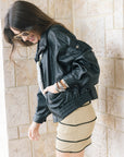 Early oversized faux leather coat on a model with a silver bag and mini dress wearing sunglasses, side