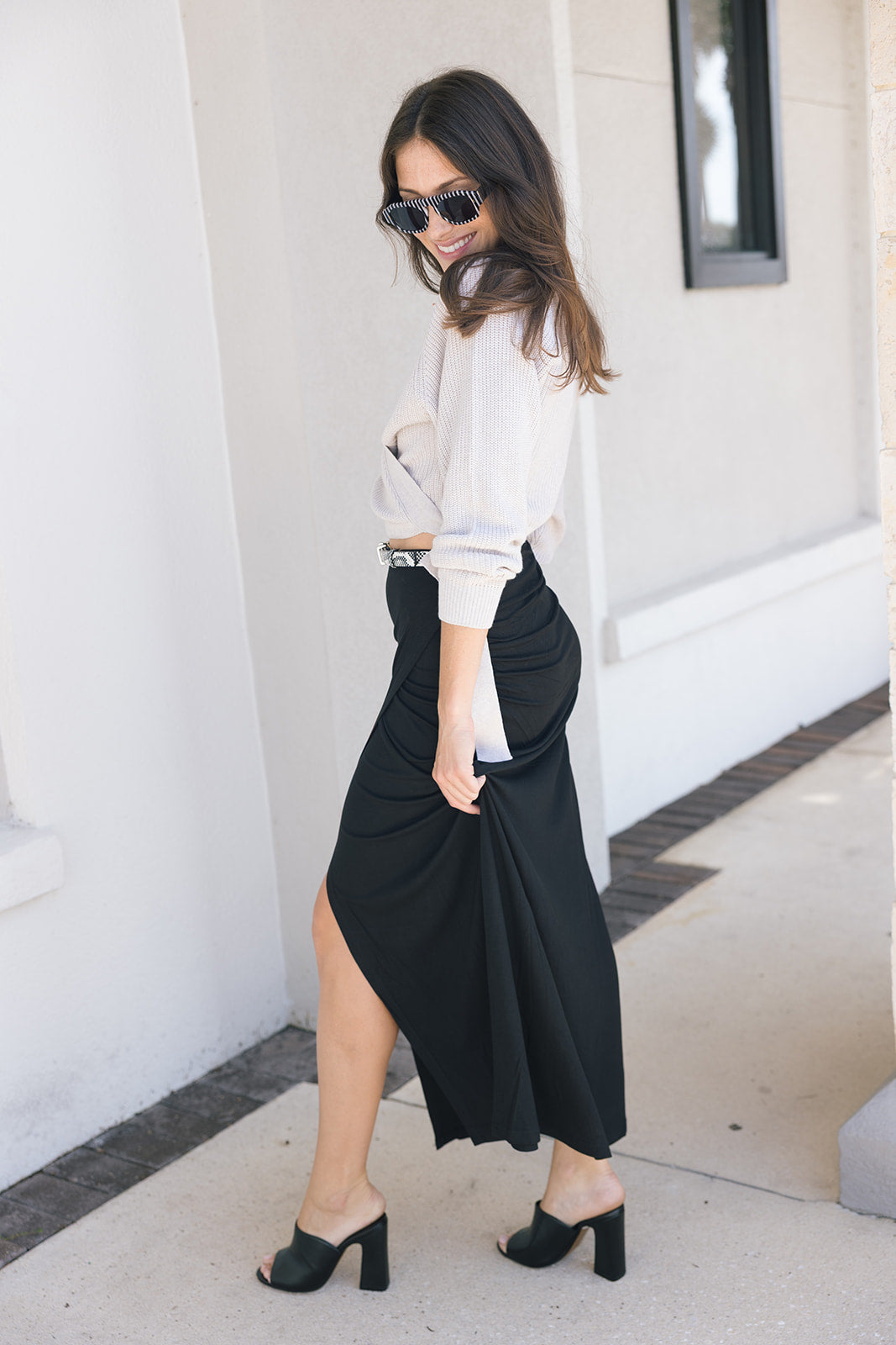 Fizz long drape skirt on a model with a cream wrap sweater and black heels side view