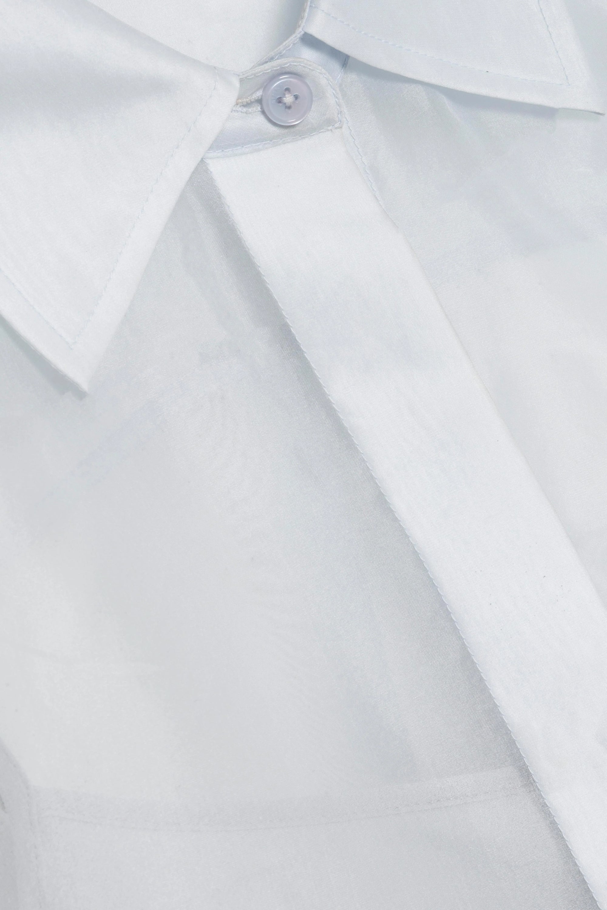 Close-up of a blue sheer shirt with a collar and button on a light gray background