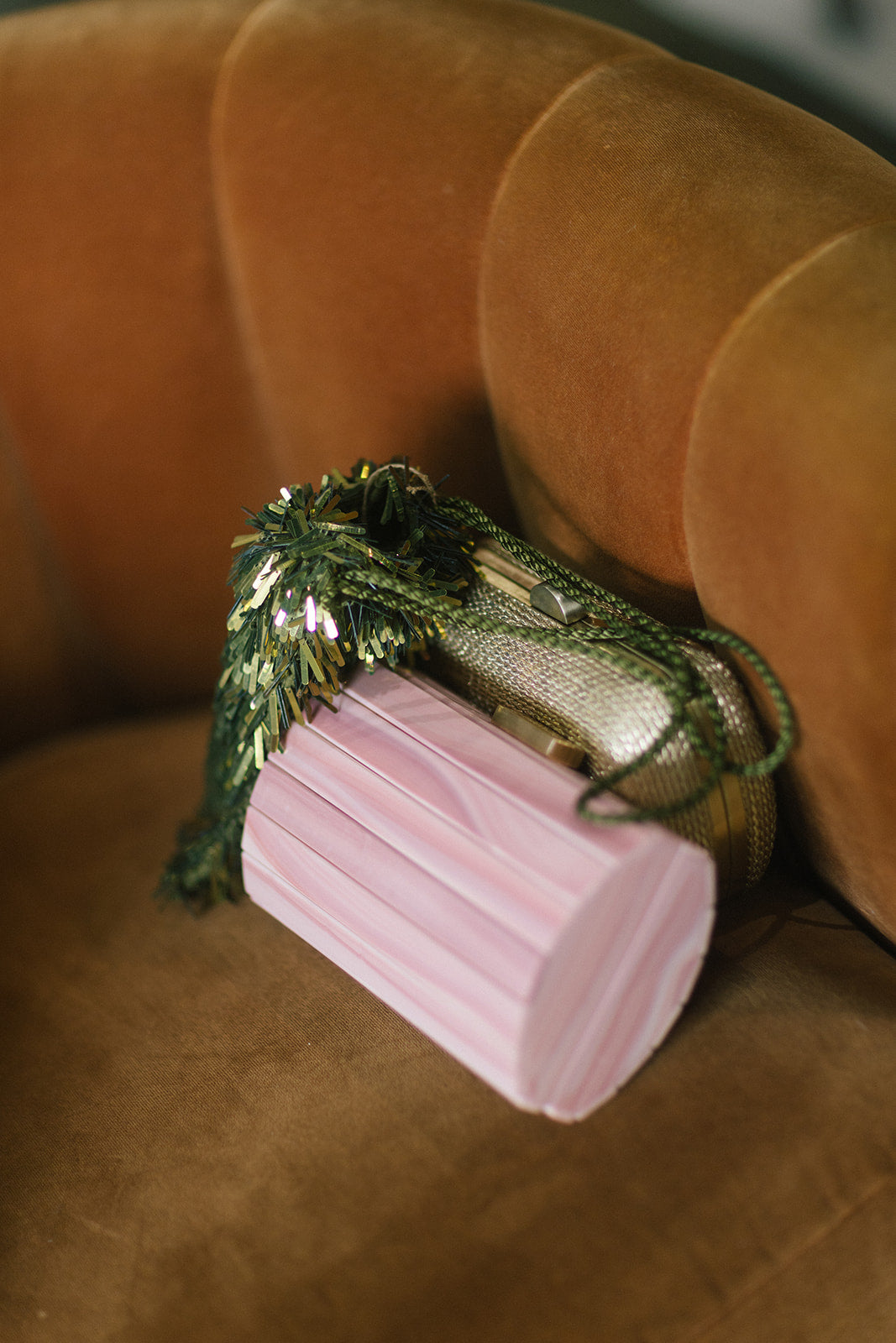 a pink, gold, and green bag sitting in a gold chair 