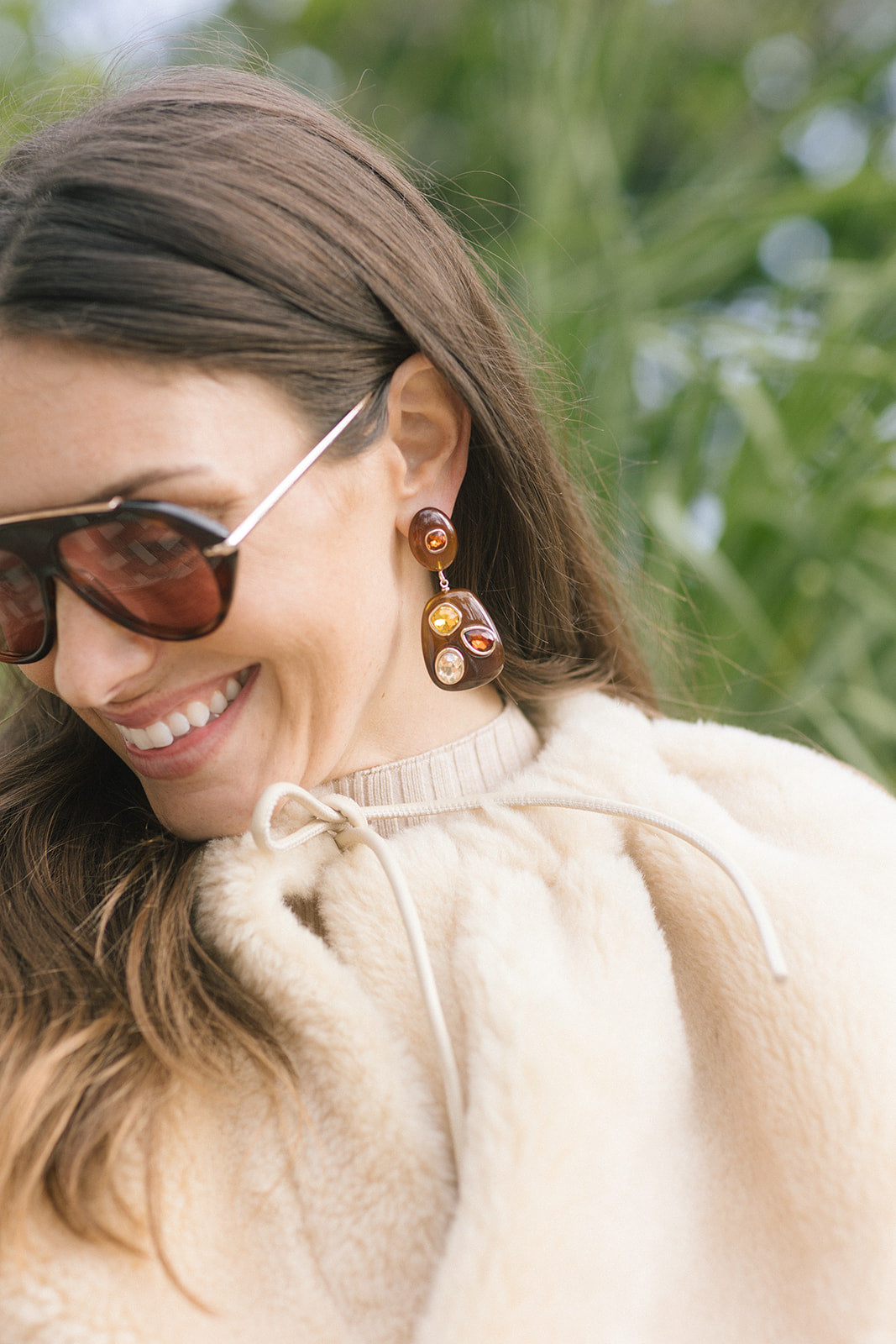 model wearing sunglasses and brown drop earrings with multi color stones 