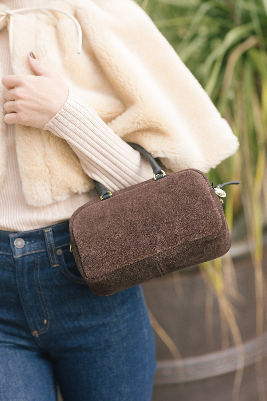 model holding a small rectangle suede brown bag 
