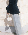 model wearing light blue jeans covered in rhinestones and a dark blazer holding a purse, side view