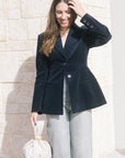 model wearing a navy blazer withe rhinestone jeans holding a cream bag, outside