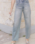 model wearing light blue jeans covered in rhinestones and a white top holding a purse 