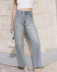 model wearing light blue jeans covered in rhinestones and a white top holding a purse 