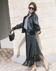 model wearing a black jacket with a grey top paired with a black skirt with fringe at the bottom 