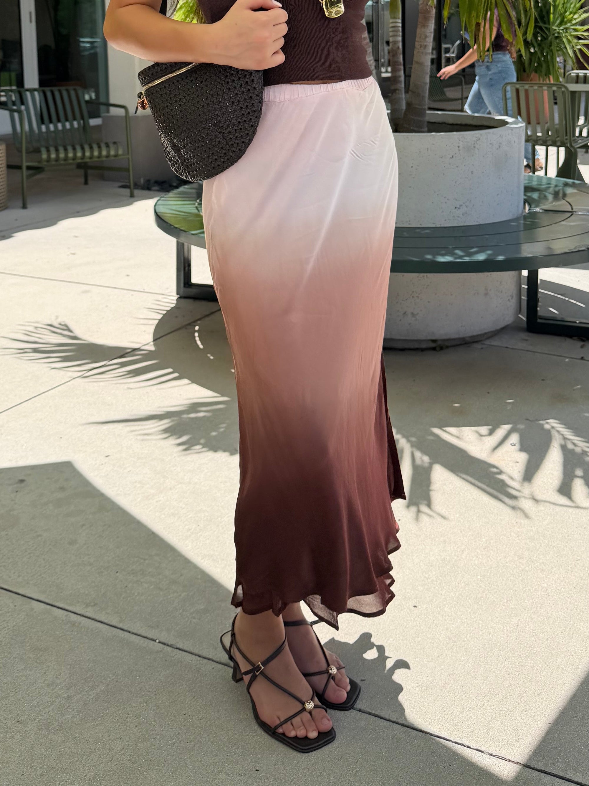 A woman stands outdoors on a patio wearing a sleeveless ombre maxi skirt 