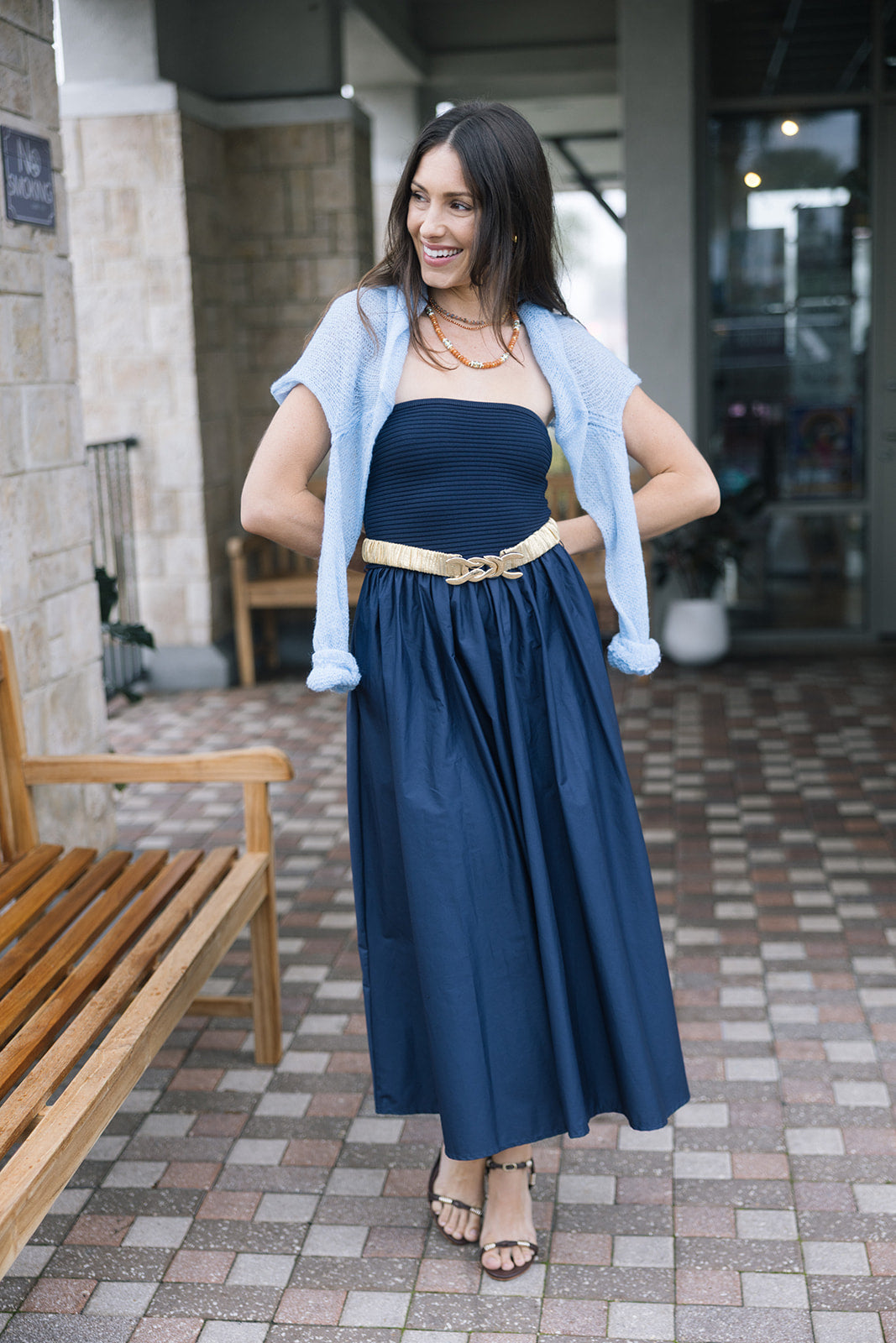 Navy blue dress with Nixie Pullover over model's shoulders, full body view