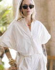 Person wearing a cream outfit with Jordan Sunglasses Nikko Tortoise + 12K Polarized in an outdoor setting