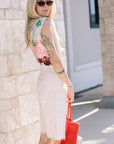 Woman wearing a Liset One Piece and The Half-Pipe Bermuda Fray Peach Puree, holding a red bag against a stone wall.