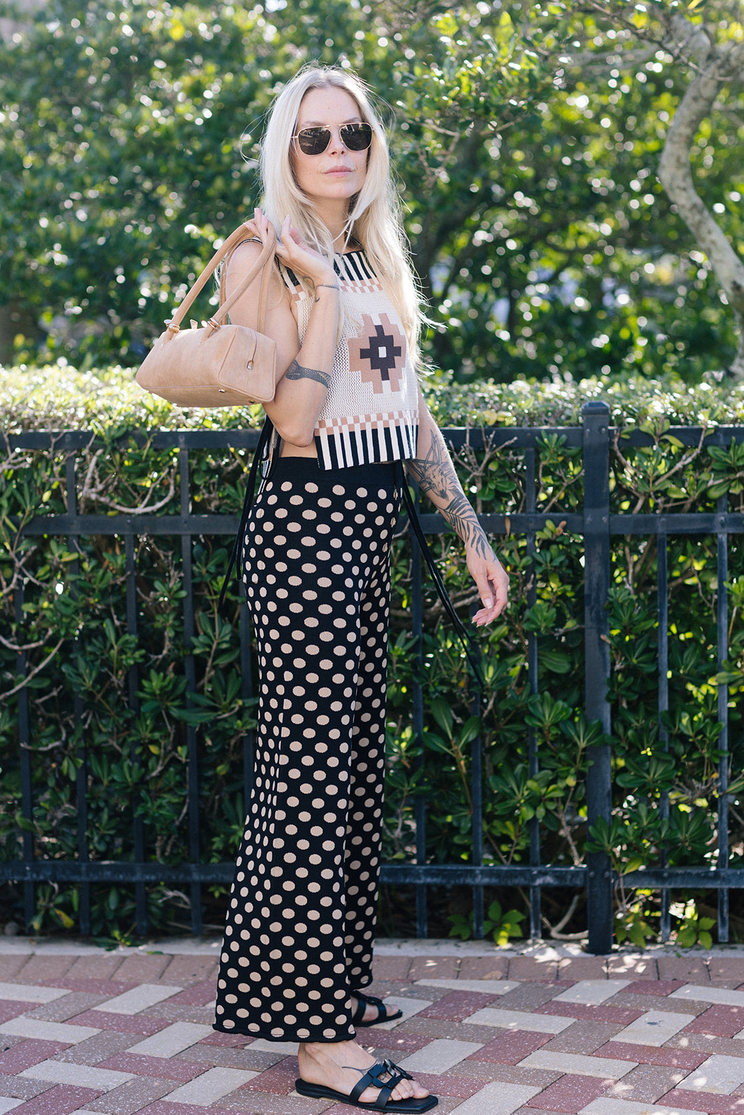Woman wearing Cleo Chacana Top with geometric patterns and a black polka dot pants outdoors.