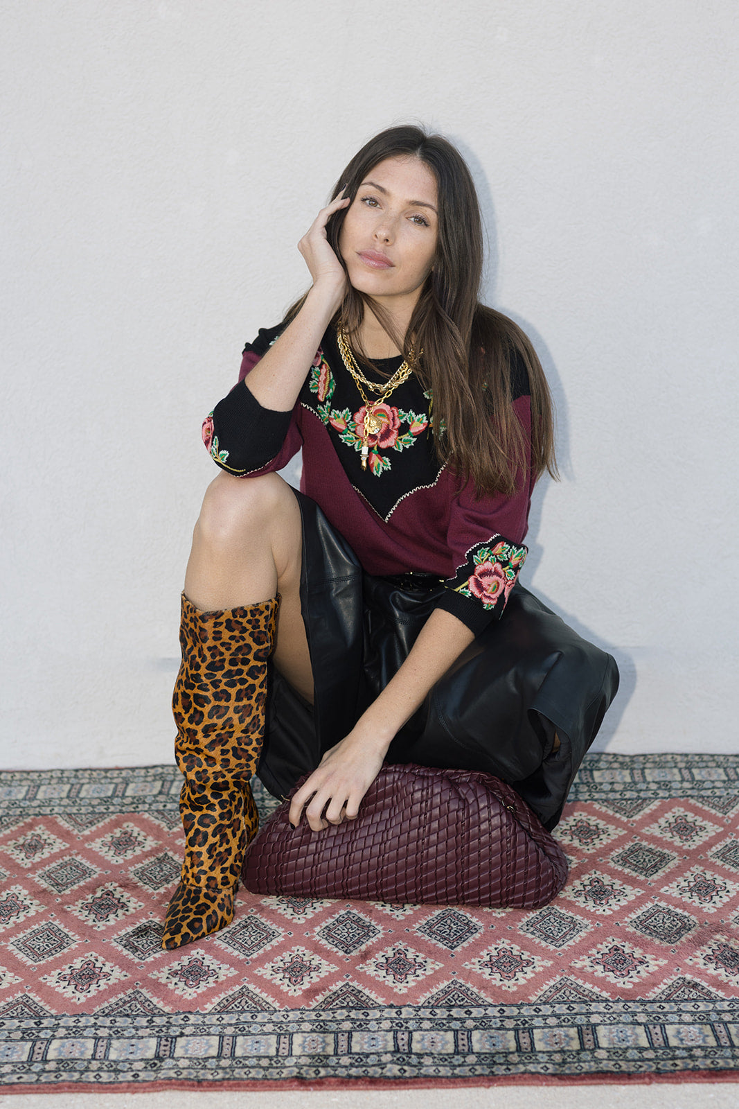 Model crouching with vino bag and cheetah boots