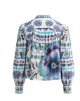 A long-sleeve blouse shown from the back, featuring a cream base with a vibrant blue, purple, and green floral and geometric pattern, back