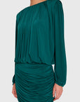 A woman wearing a dark teal green off-the-shoulder long-sleeve mini dress with ruched draping details, shown from the neck down against a light gray studio background.