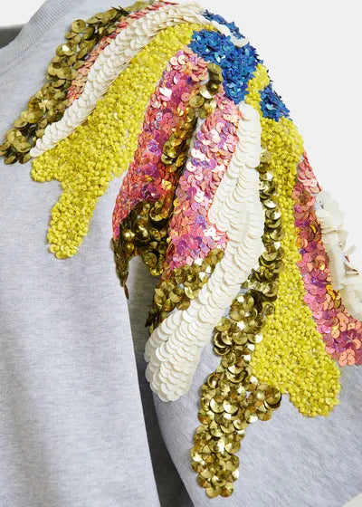 Colorful sequin headband with gold, pink, blue, and yellow patterns on a gray background.