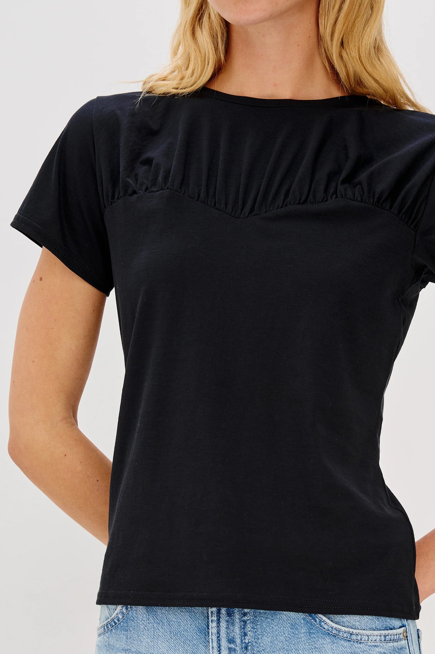 Black ruffled blouse worn by a person on a white background front view 