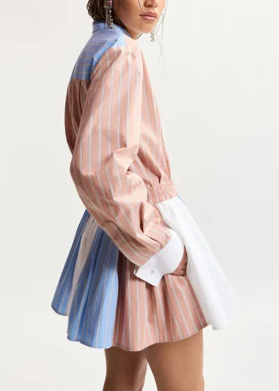 Person wearing a pink and blue striped outfit on a light background
