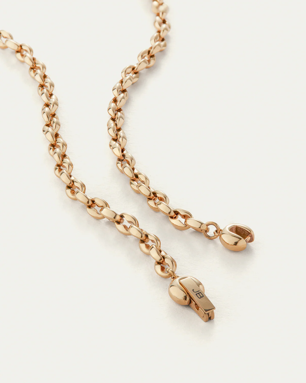 Rose gold chain necklace with a small pendant on a light beige background