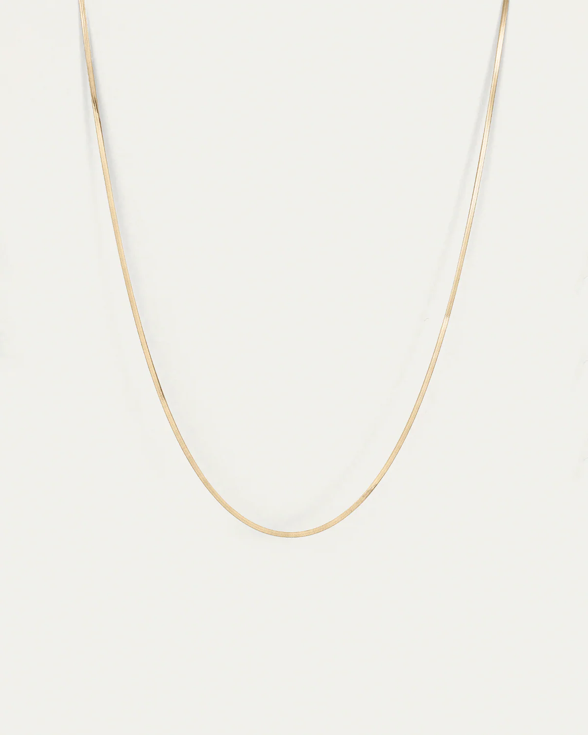 Gold chain necklace on a light gray background